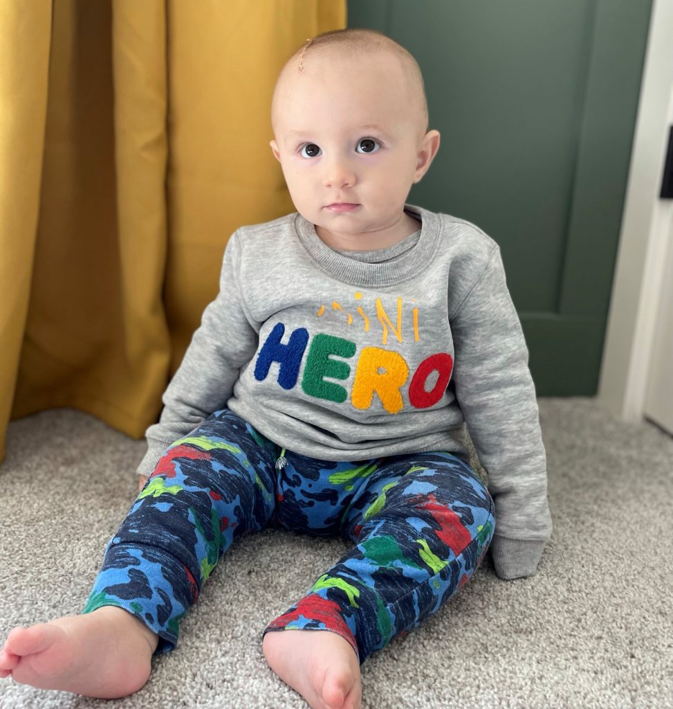 Mitchell sitting on the floor wearing a shirt with the word hero on it.