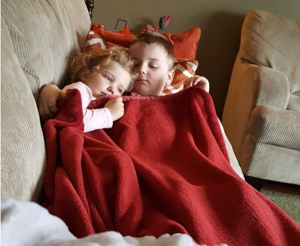 Alexander and his sister Victoria laying under a blanket together.