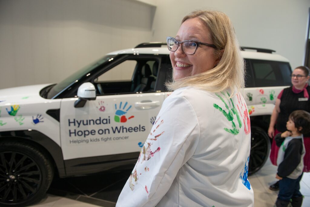 Dr. Chopek wears a lab coat with colourful handprints