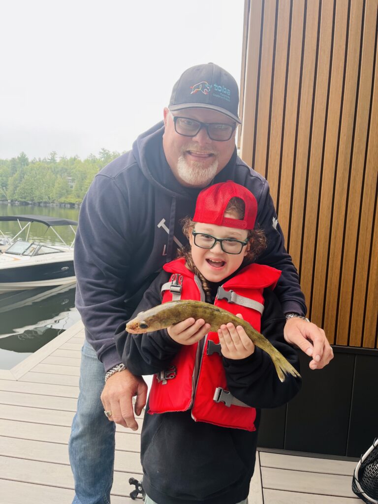 Jack holds a fish and poses beside Ken.