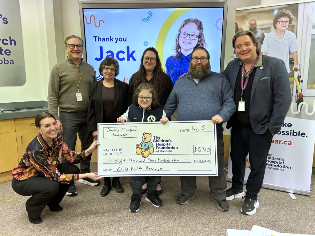 Jack and his parents present a large cheque to the CEOs of Children's Hospital Research Institute of Manitoba.