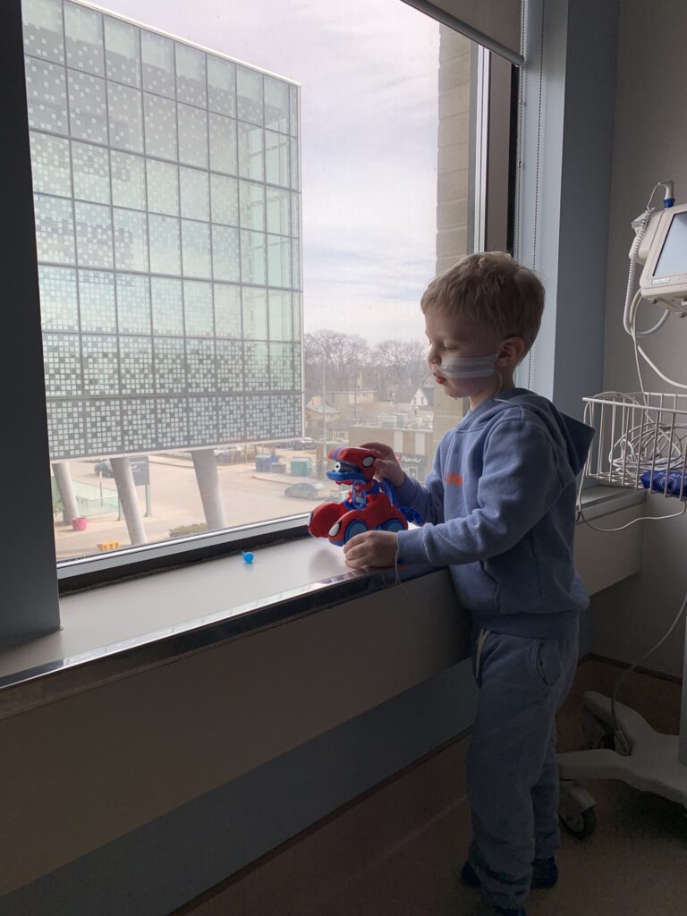 Calvin plays with a red toy beside the hospital window.