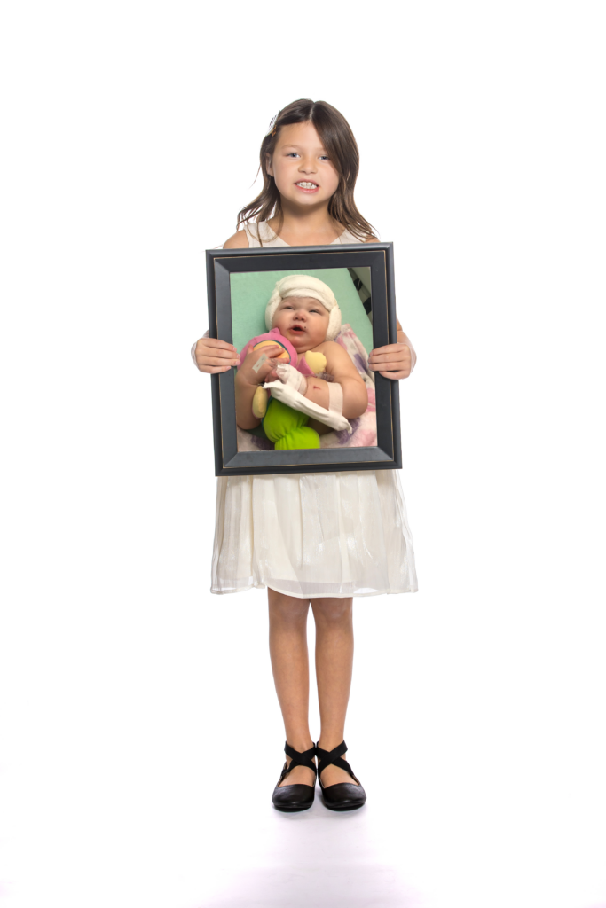 Ireland holds a framed photo of her as a baby in the hospital after surgery.