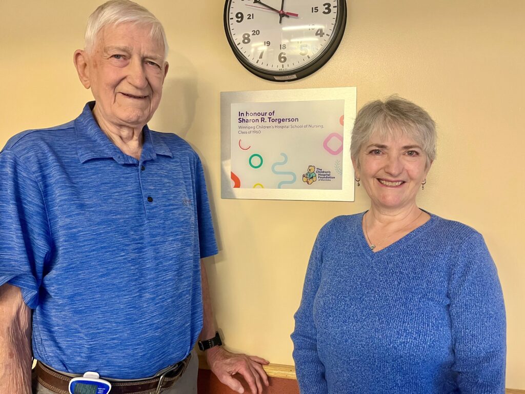 Sharon's husband Glen and their daughter Kelly pose next to a plaque in Sharon's honor.