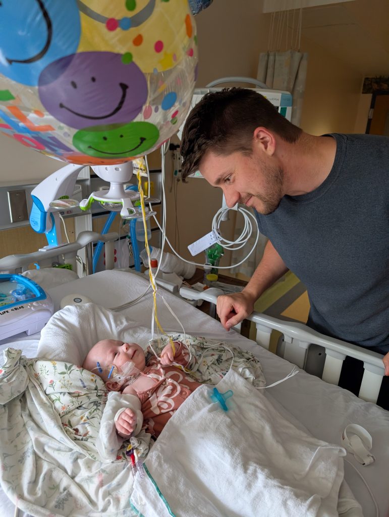 Baby Juliette smiles at her dad from her hospital bed after surgery.