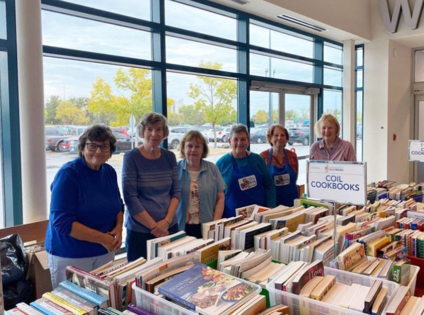 Volunteers stand behind a table of books at the Children's Hospital Book Market.