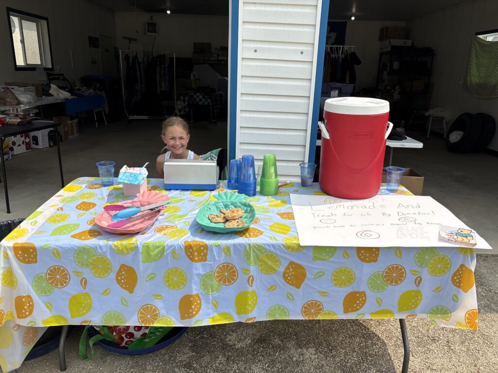 Macy sitting at her lemonade stand.